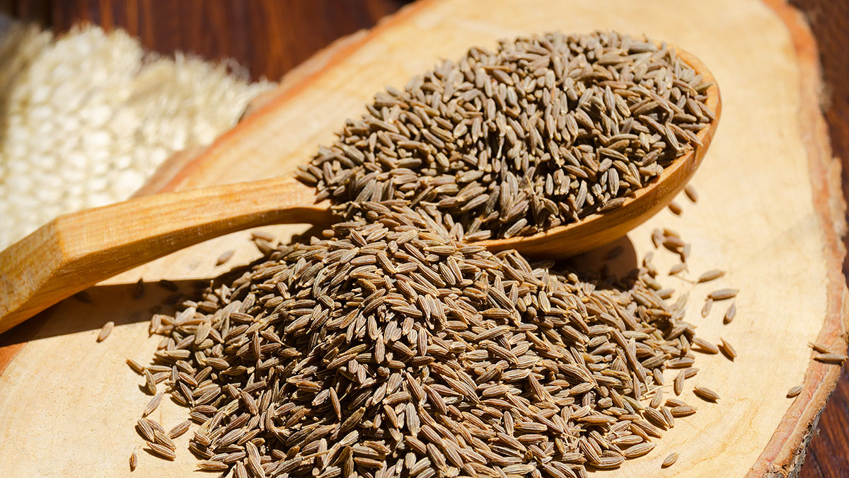 Oriental spice zira. Cumin on a spoon on a wooden board.