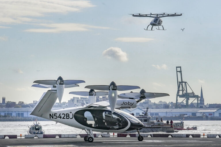 FILE - An electric vertical takeoff and landing (eVTOL) aircraft, flies above the Joby eVTOL aircraft, during a demonstration of eVTOLs Nov. 13, 2023, in New York. (AP Photo/Bebeto Matthews, File)