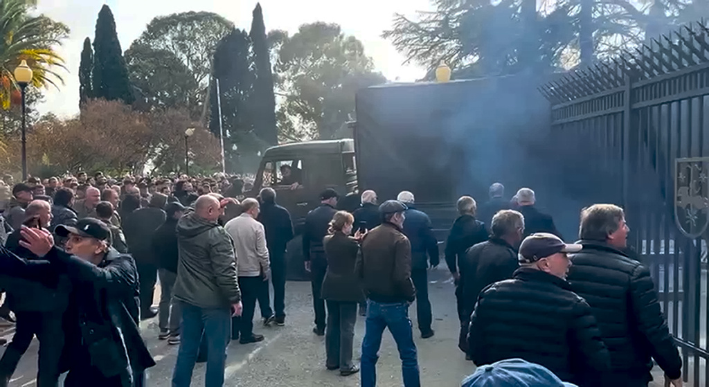 In this photo taken from video released by the Information Center of the President of the Republic of Abkhazia, a Protesters' truck breaks through the closed gate in the fence outside the parliament building of the Georgian separatist region of Abkhazia as tensions flared over a proposed pact that would allow Russians to buy apartments in the region, Georgia, on Friday, Nov. 15, 2024, (Information Center of the President of the Republic of Abkhazia via AP)