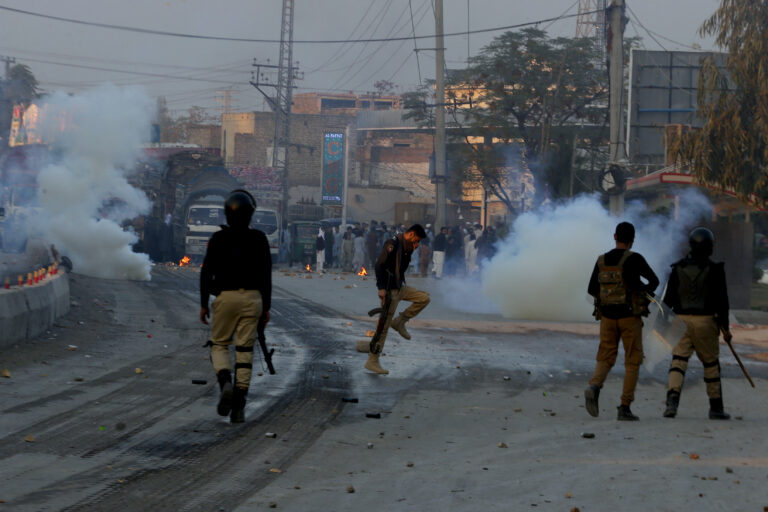 Police officers fire tear gas shells to disperse angry protestors, who blocked a road near a police station and demanding to handover them an arrested man, accused of insulting Islam's holy book, the Quran, in Peshawar, Pakistan, Tuesday, Nov. 19, 2024. (AP Photo/Muhammad Sajjad)