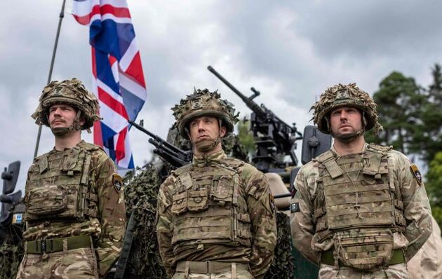 British soldiers stand in front of a military vehicle during a press conference of the Polish and Lithuanian president following a joint visit of the NATO Multinational Division North East mobile command center near Szypliszki village, located in the so-called Suwalki Gap - an 80-kilometer stretch of the Polish-Lithuanian border sandwiched between Kaliningrad and Belarus, in north-eastern Poland, on July 7, 2022. (Photo by Wojtek RADWANSKI / AFP) (Photo by WOJTEK RADWANSKI/AFP via Getty Images)