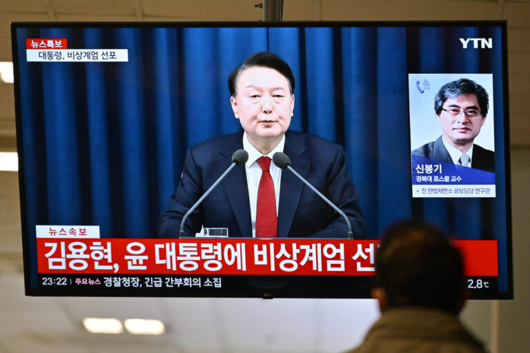 A man watches South Korea's President Yoon Suk Yeol speak during a news broadcast on a television at a train station in Seoul on December 3, 2024, after he declared emergency martial law, saying the step was necessary to protect the country from "communist forces" amid parliamentary wrangling over a budget bill. "To safeguard a liberal South Korea from the threats posed by North Korea's communist forces and to eliminate anti-state elements... I hereby declare emergency martial law," Yoon said in a live televised address to the nation. (Photo by Anthony WALLACE / AFP)