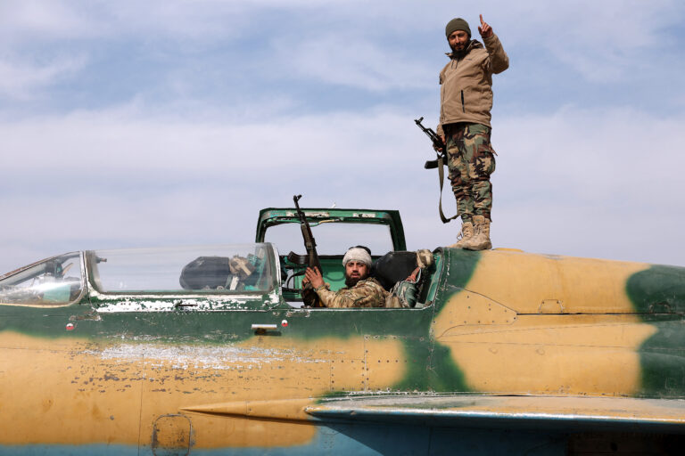 Anti government fighters gesture as they check a Syrian army jet after they took over a military airbase near the central city of Hama, on December 6, 2024. Rebel forces pressing a lightning offensive in Syria aim to overthrow President Bashar al-Assad's rule, their Islamist leader said in an interview published on December 6. In little over a week, the offensive has seen Syria's second city Aleppo and strategically located Hama fall from Assad's control for the first time since the civil war began in 2011. (Photo by OMAR HAJ KADOUR / AFP)