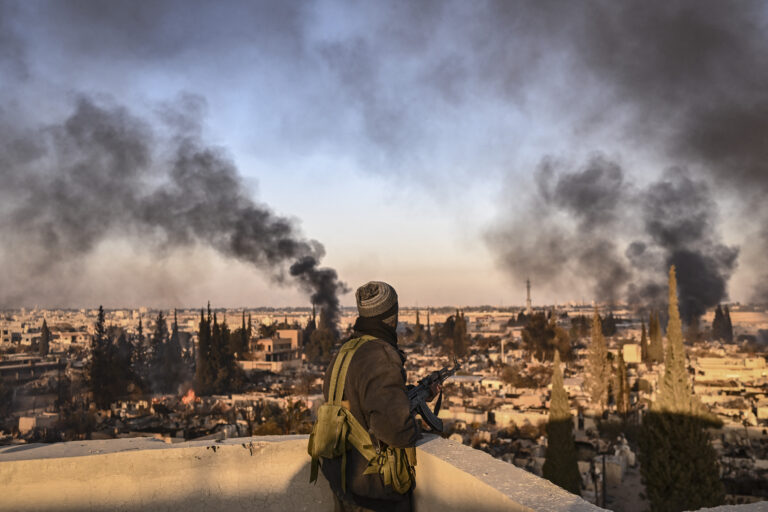 A gunman stands on the roof of a building to push away looters from the Najha military housing complex in southeast Damascus on December 17, 2024. Islamist-led rebels took Damascus in a lightning offensive on December 8, ousting president Bashar al-Assad and ending five decades of Baath rule in Syria. (Photo by Aris MESSINIS / AFP)