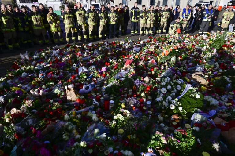 Members of Magdeburg's fire department stand at a makeshift memorial outside the Johanniskirche (Johannes Church), near the site of a car-ramming attack on a Christmas market in Magdeburg, eastern Germany, on December 22, 2024. The death toll in the attack on December 20, rose to 5 on December 21, 2024, with over 200 injured, according to the head of the regional government, Reiner Haseloff. (Photo by John MACDOUGALL / AFP)