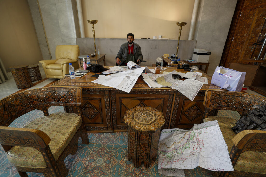 A Syrian opposition fighter sits inside an office at the Presidential Palace after the Syrian government collapsed in Damascus, Syria, Sunday, Dec. 8, 2024. (AP Photo/Omar Sanadiki)