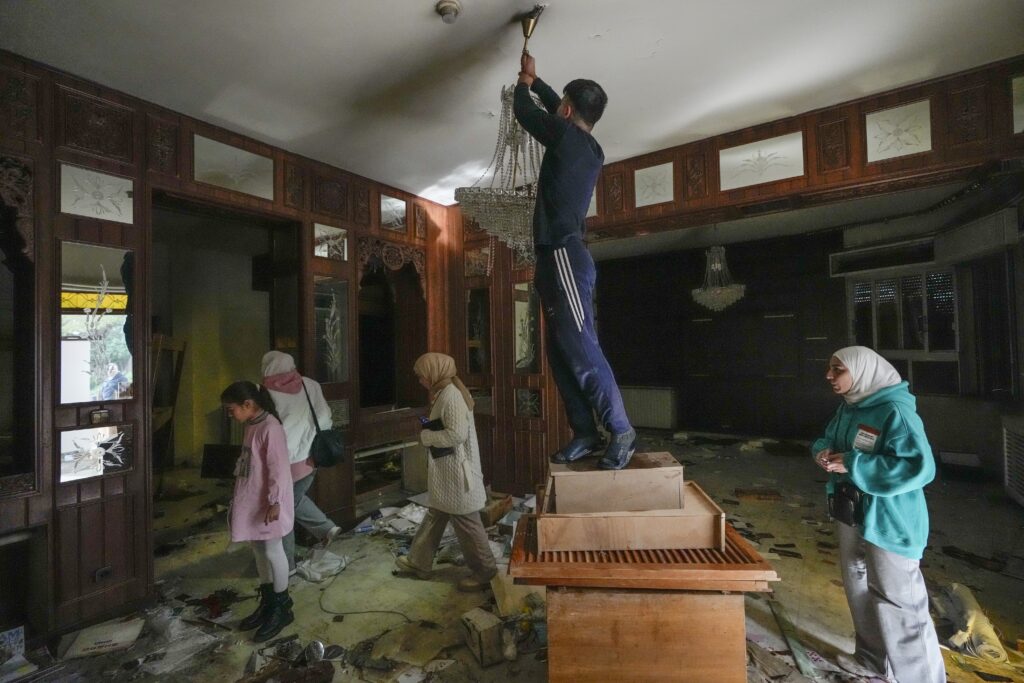 A man tries to take a lamp as people search for belongings in the ransacked private residence of Syrian President Bashar Assad in the Malkeh district of Damascus, Syria, on Sunday, Dec. 8, 2024. (AP Photo/Hussein Malla)