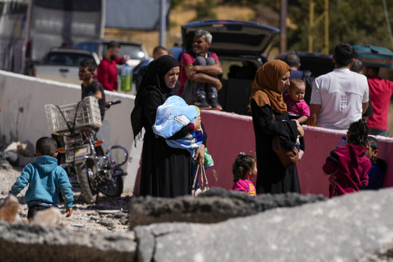 FILE - People carry their luggage as they cross into Syria on foot, through a crater caused by Israeli airstrikes aiming to block Beirut-Damascus highway at the Masnaa crossing, in the eastern Bekaa Valley, Lebanon, Saturday, Oct. 5, 2024. (AP Photo/Hassan Ammar, File)