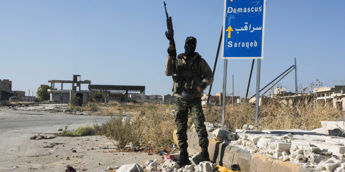 A rebel fighter carries a weapon as he stands at the entrance of Saraqeb town in northwestern Idlib province, Syria December 1, 2024. REUTERS/Mahmoud Hassano