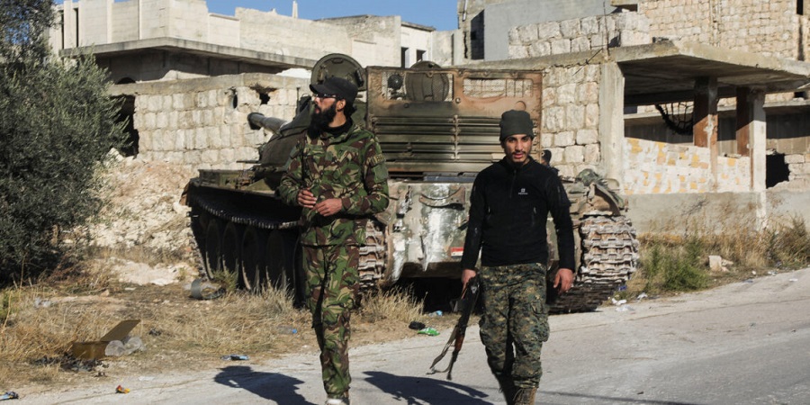 Rebel fighters walk near a military vehicle in Maarat al-Numan in Idlib province, Syria December 1, 2024. REUTERS/Mahmoud Hassano