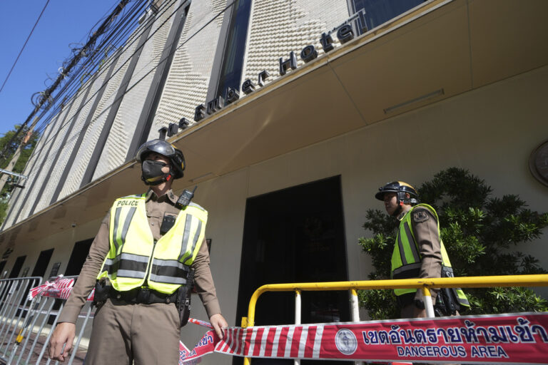 Policemen stand guard after a hotel fire in Bangkok, Thailand, Monday, Dec. 30, 2024. (AP Photo/Sakchai Lalit)