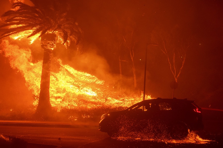 A car drives past flames from the Franklin Fire at Pepperdine University in Malibu, Calif., Tuesday, Dec. 10, 2024. (AP Photo/Eric Thayer)