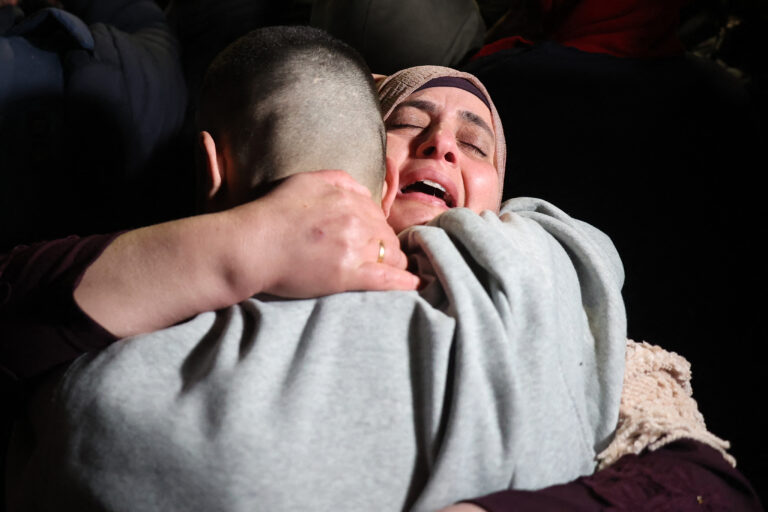 A Palestinian woman embraces her freed son upon his arrival among some 90 prisoners set free by Israel in the early hours of January 20, 2025, in the occupied West Bank town of Beitunia, on the outskirts of Ramallah. Crowds cheered, chanted and honked car horns as two buses carrying the prisoners arrived in Beitunia following their release as part of the Gaza ceasefire deal that began on January 19 and saw three Israeli hostages freed by Hamas in the Gaza Strip. (Photo by Zain JAAFAR / AFP)