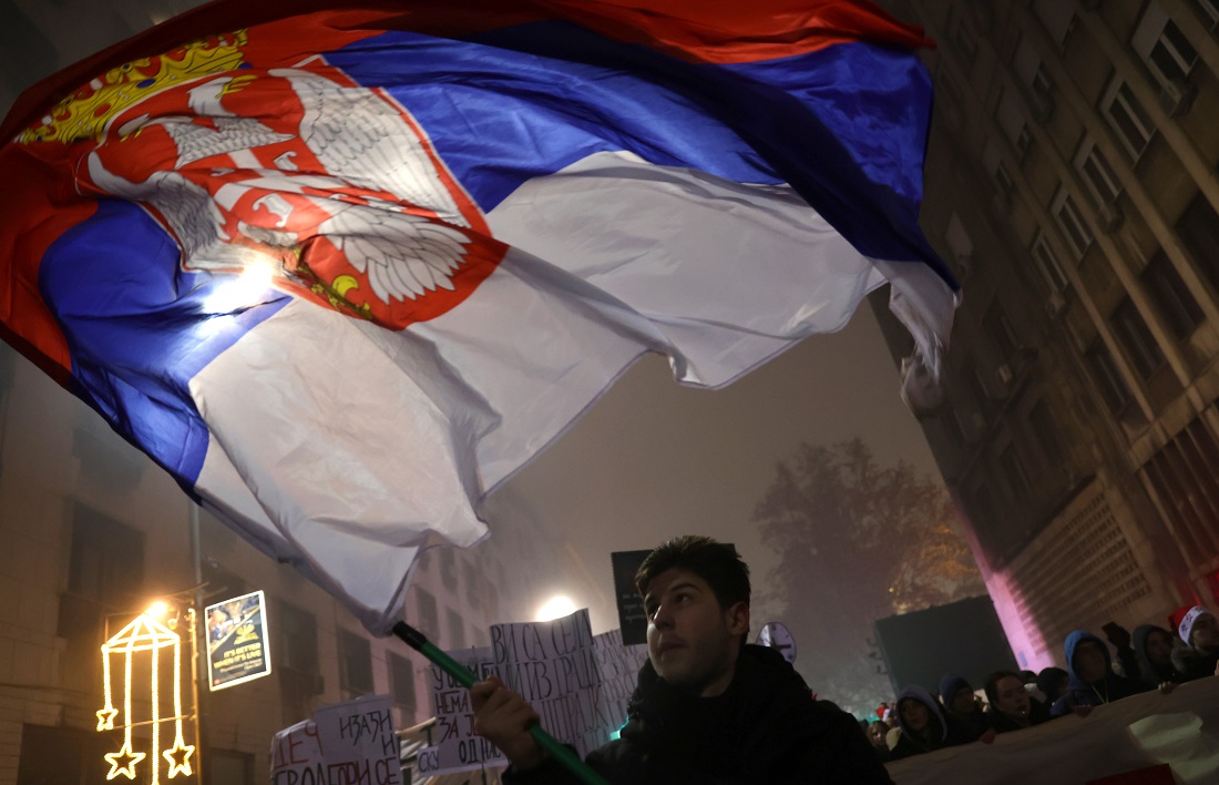 epa11800571 A protestor waves a Serbian flag during a protest rally in Belgrade, Serbia, 31 December 2024. University students staged a protest asking for accountability after fifteen people lost their lives in the collapse of the Novi Sad Railway Station canopy on 01 November 2024. The station building, which had been renovated and reopened on 05 July 2024, was undergoing further renovations shortly before the collapse.  EPA/ANDREJ CUKIC