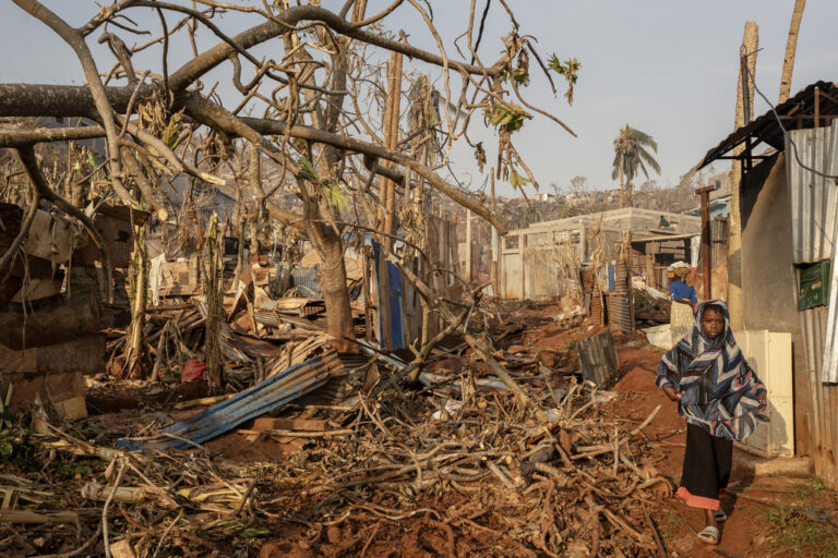 A girl walks amidst destruction in Mbouyougou, Mayotte, Saturday, Dec. 21, 2024. (AP Photo/Adrienne Surprenant)