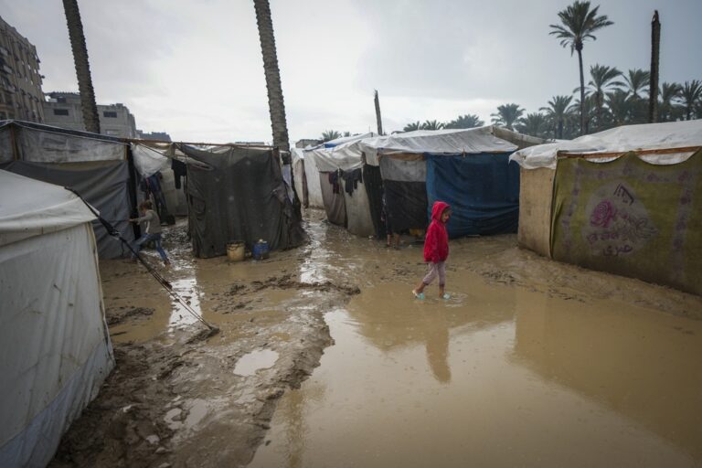 A young girl walks through a flooded street following overnight rainfall at the refugee tent camp for displaced Palestinians in Deir al-Balah, central Gaza Strip, Tuesday, Dec. 31, 2024. (AP Photo/Abdel Kareem Hana)