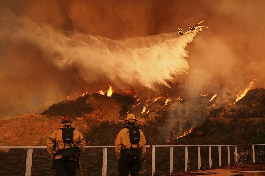 Firefighters watch as water is dropped on the Palisades Fire in Mandeville Canyon on Saturday, Jan. 11, 2025, in Los Angeles. (AP Photo/Jae C. Hong)