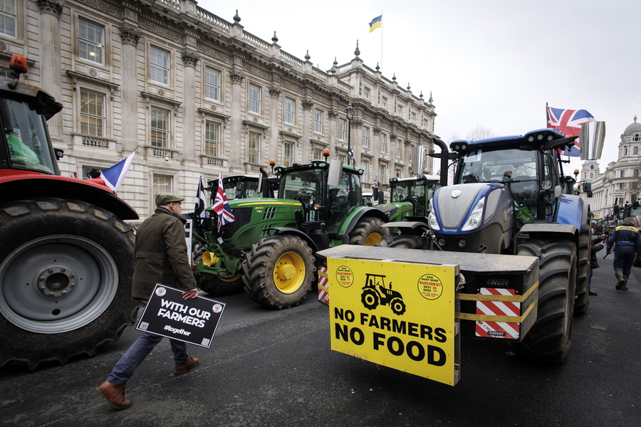 epa11886611 A protester carrying a placard walks through tractors as British farmers gridlock Whitehall during a protest over changes to inheritance tax (IHT) rules, in London, Britain, 10 February 2025. British farmers demand a reversal of the changes to inheritance tax rules announced in the October 2024 budget by the Labour government, which will introduce new taxes on farms worth more than 1 million GBP that would apply from April 2026.  EPA/TOLGA AKMEN