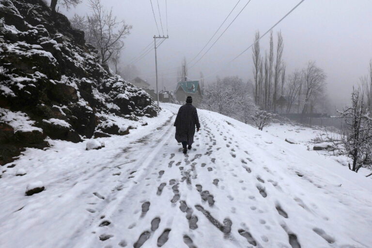 epa11929371 A person walks on a snow-covered road on the outskirts of Srinagar, India, 28 February 2025. The plains and upper reaches received fresh snowfall and rain, bringing much-needed relief from a prolonged dry spell.  EPA/FAROOQ KHAN