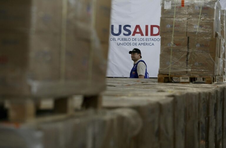 FILE - A man walks past boxes of USAID humanitarian aid at a warehouse at the Tienditas International Bridge on the outskirts of Cucuta, Colombia, Feb. 21, 2019, on the border with Venezuela. (AP Photo/Fernando Vergara)