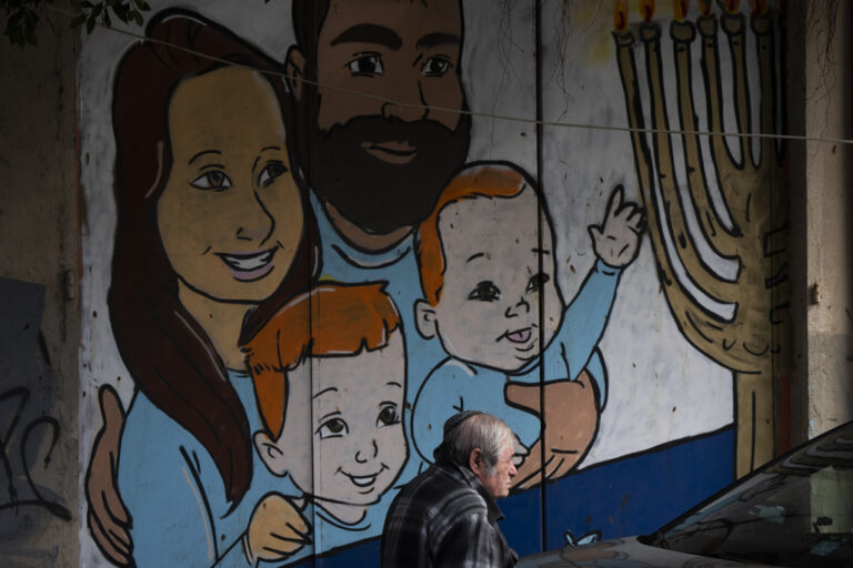 A man walks past graffiti of Shiri and Yarden Bibas and their sons, Ariel, left, and Kfir, right, who were taken captive by Hamas, in Tel Aviv, Israel, Wednesday, Feb. 19, 2025. Yarden Bibas was freed from captivity earlier this month. (AP Photo/Oded Balilty)