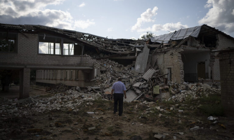 Oleksandr Pishchyk, a school director, stands in front of the school library that was destroyed by shelling in Kupiansk, Ukraine, Wednesday, Aug. 23, 2023. There are still 451 children in Kupiansk who's parents have refused evacuation pleas, despite intensified offensive operations by Russian forces in recent weeks. (AP Photo/Bram Janssen)