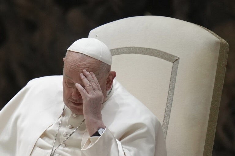 Pope Francis touches his forehead during his weekly general audience in the Paul VI Hall, at the Vatican, Wednesday, Feb. 12, 2025. (AP Photo/Alessandra Tarantino)